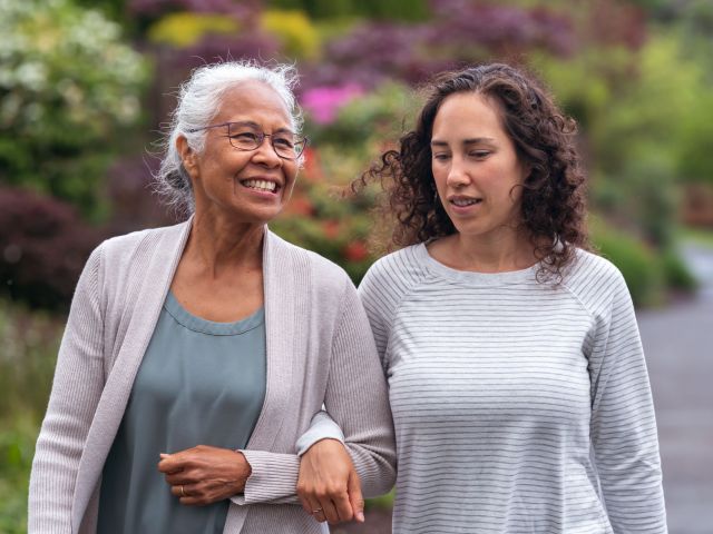 Mixed race mother and daughter walk and talk together outside